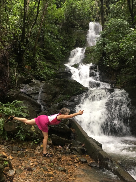 Person striking a pose near a cascading waterfall.