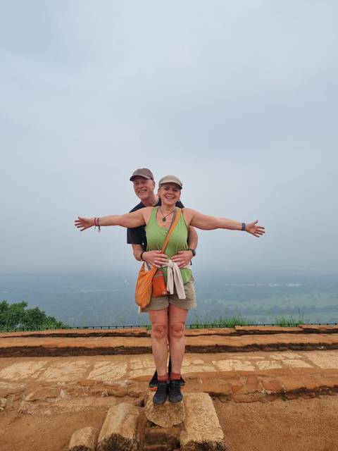 Couple posing at a viewpoint with cloudy sky in the background.