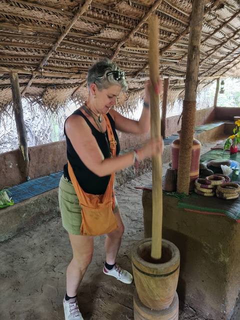 Person pounding with a pole in a traditional setting.