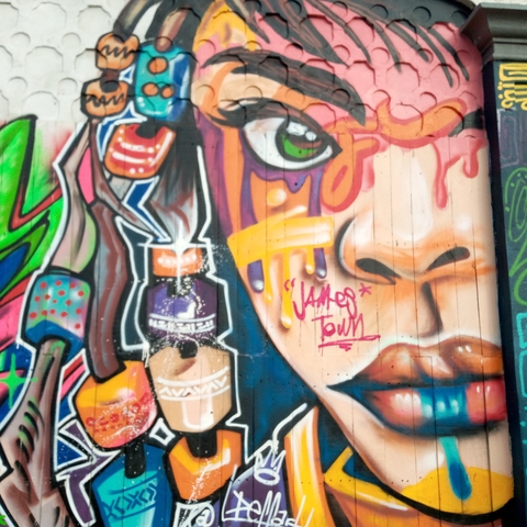 Colourful street-art mural featuring a stylised face and the words "James Town" on a wooden wall.
