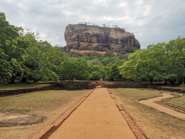 View of Sigiriya rock formation surrounded by trees.
