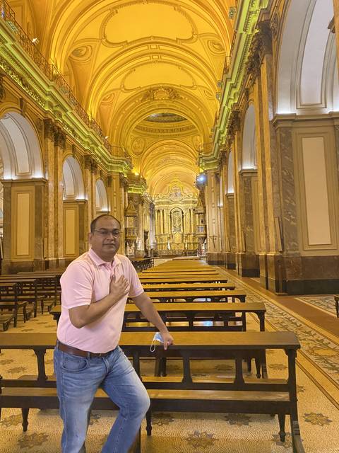 A man sitting on a bench inside a beautifully decorated church.