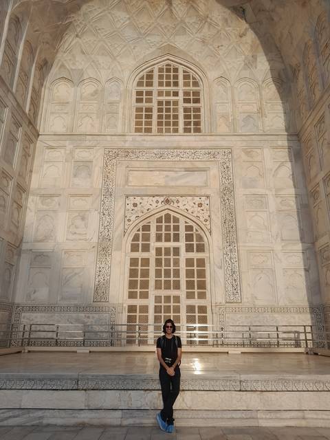 Person posing against intricately carved marble structure.