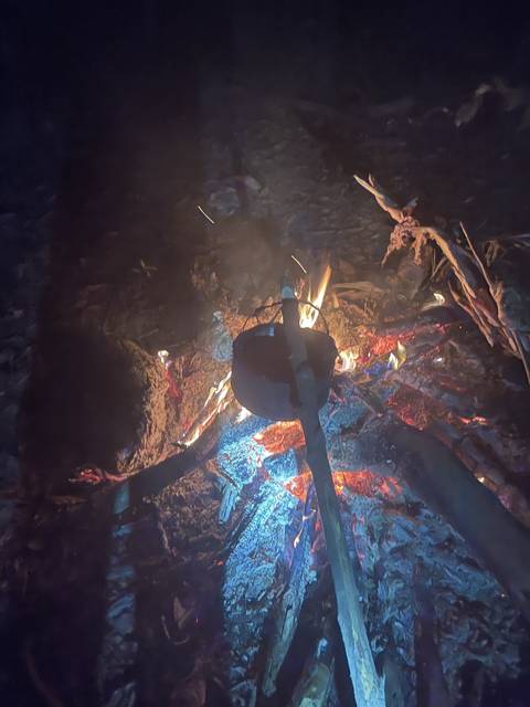 Cooking pot over a campfire at night.