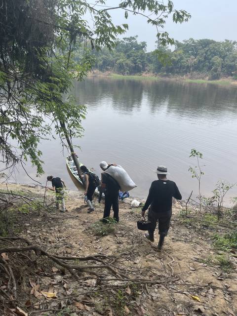 Group of people with bags near a riverbank.