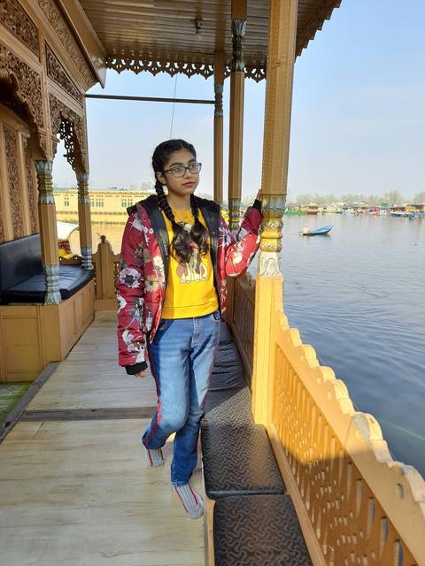 Person standing on a boat holding onto a pillar.