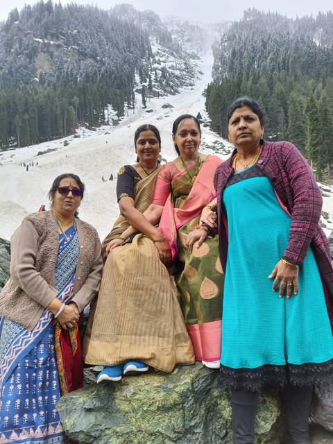 Group of women sitting on a snowy rock in a forest.
