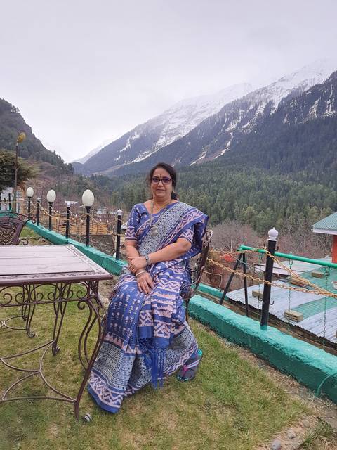 Woman sitting outside with snow-covered mountains behind.