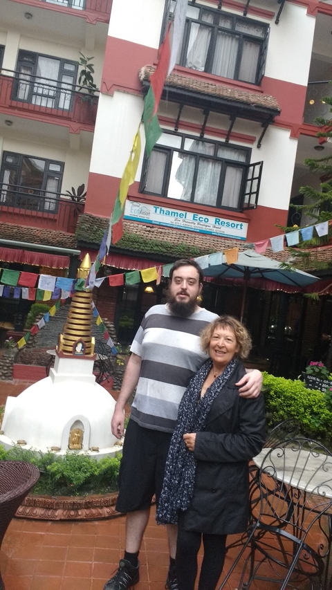 Two people posing in front of Thamel Eco Resort with Buddhist prayer flags.