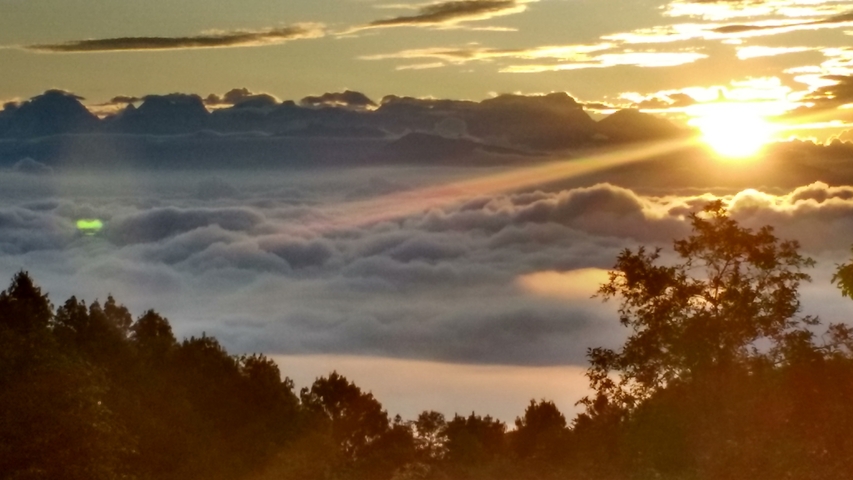 Sunrise over a cloud-filled valley with distant mountain peaks.