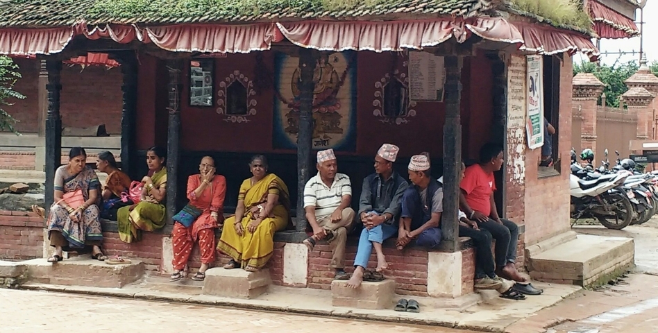 People sitting outside a small traditional building.