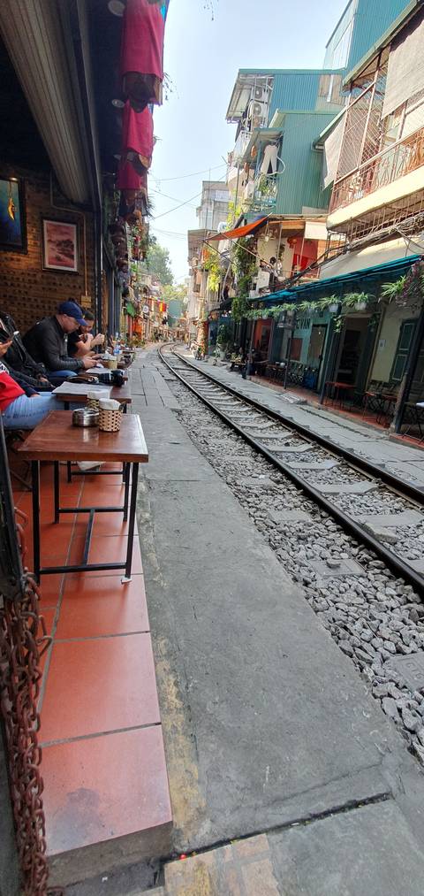 Street scene with railway track and outdoor seating.