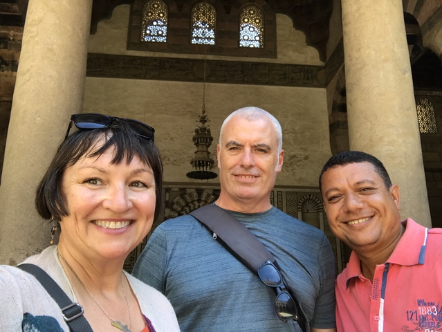 Three individuals posing in front of a historical building.