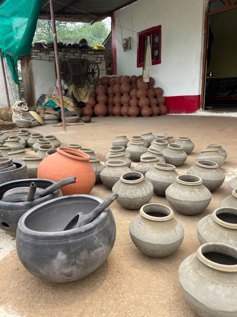 Earthen pots of various sizes and colors displayed outdoors.