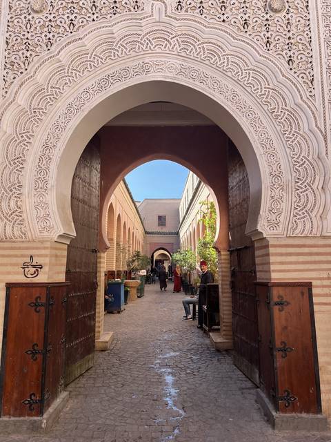 People walking through an archway in a traditional setting.