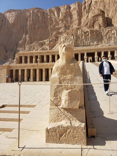 Ancient statue and columns against a mountainous backdrop in Egypt.