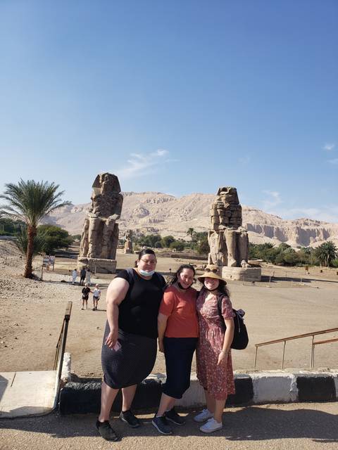 Three people posing in front of ancient statues and ruins.