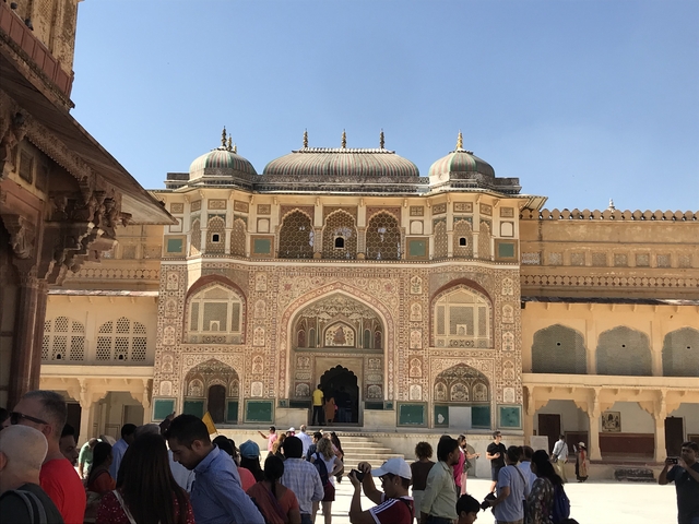People entering a historic palace facade with detailed carvings.
