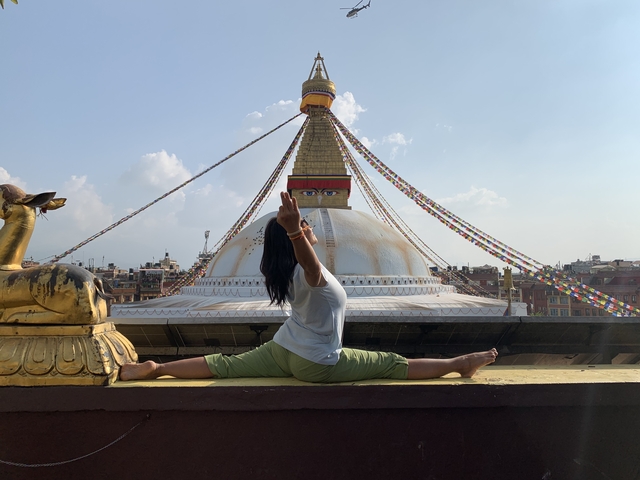 A woman doing yoga in front of the Boudhanath Stupa.