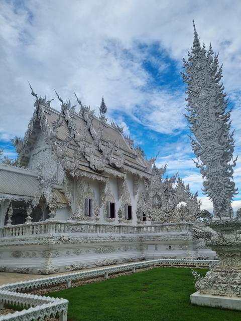 White ornate Wat Rong Khun temple with blue skies.