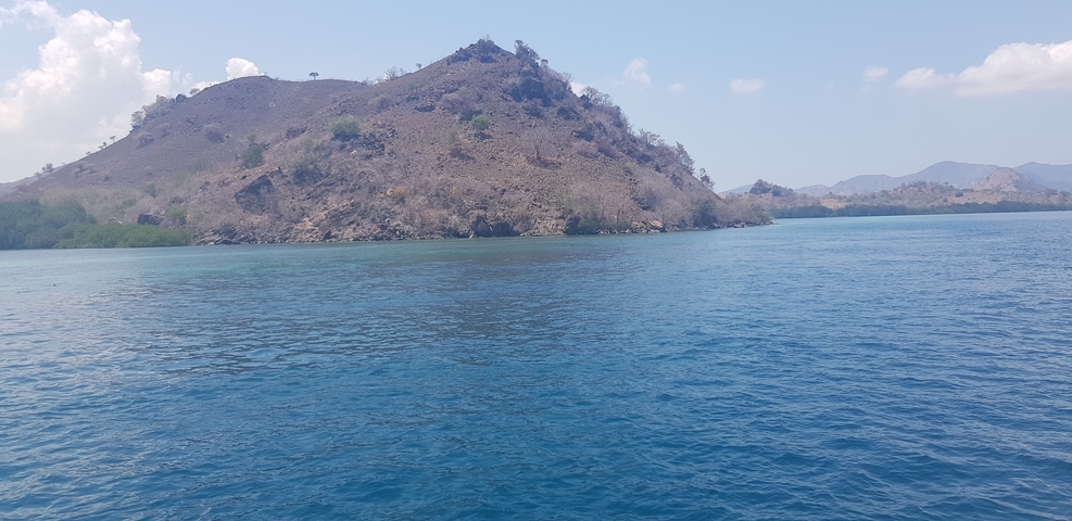 Hilly island landscape surrounded by clear blue sea.
