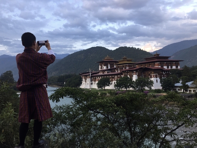Person taking a photo of a traditional Bhutanese structure.