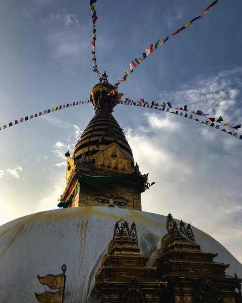 Golden stupa with prayer flags and a bright sky.