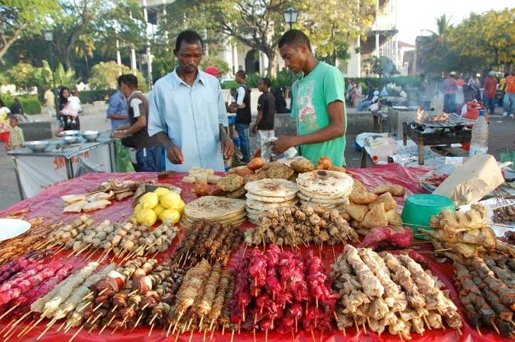 Street food vendors at a market with various grilled items.