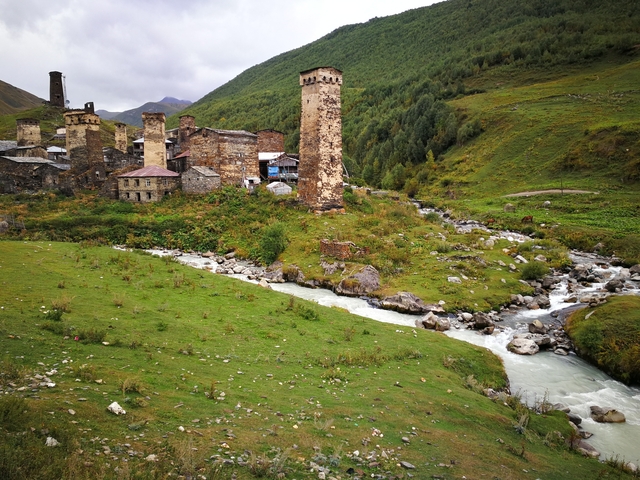 A picturesque village with medieval towers along a stream.