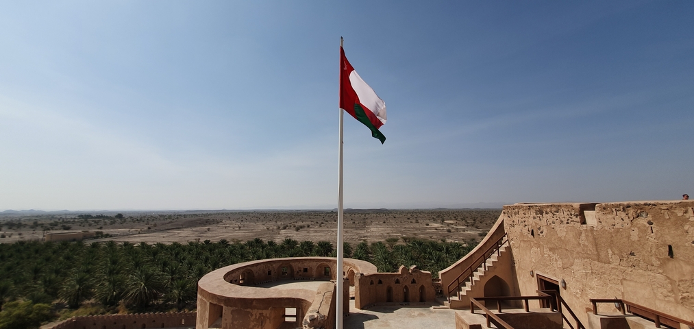 A view from a fort with an Oman flag and desert landscape.