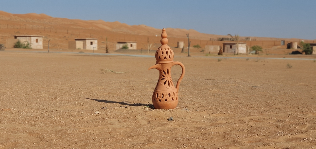 A decorative ceramic pot on sand in a desert environment.