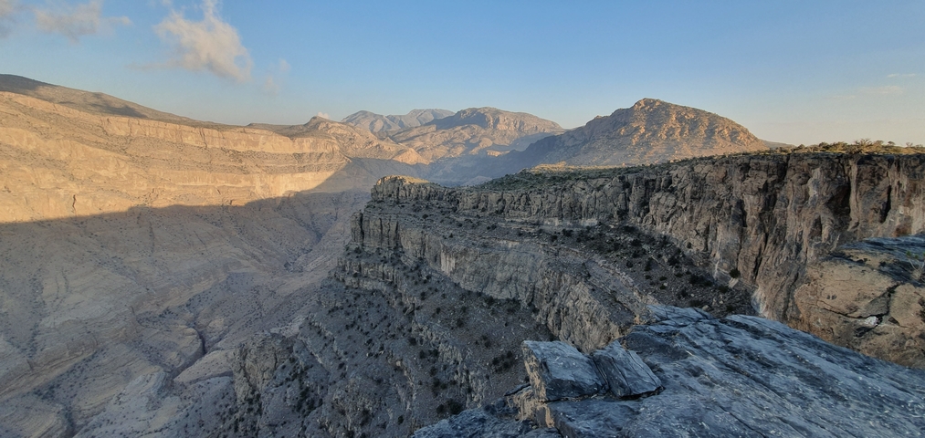 Expansive view of a canyon with steep cliffs and distant peaks.