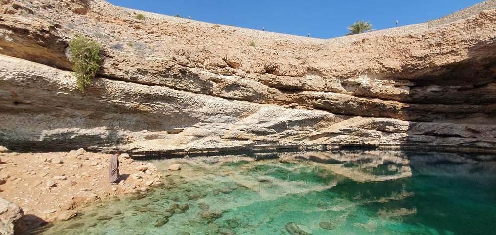 A natural sinkhole with clear blue water among rock formations.