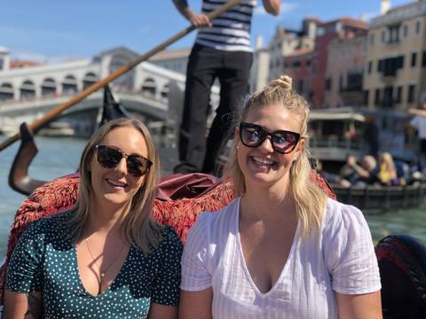 Two women smiling on a gondola ride in Venice.