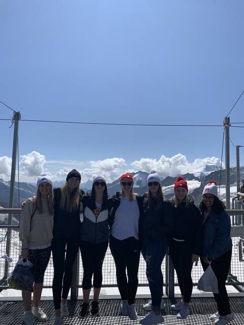 Group of people smiling with snow-capped mountains in the background.