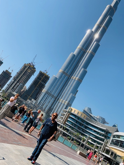 People walking near the Burj Khalifa with cranes in the background.