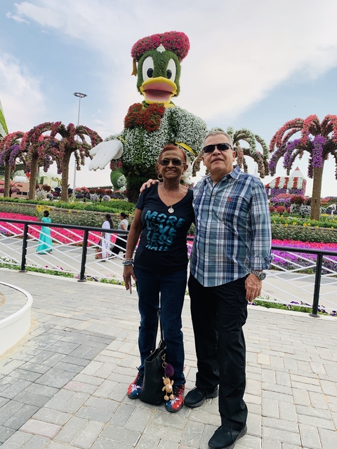 A couple posing in a colorful, flower-filled garden.