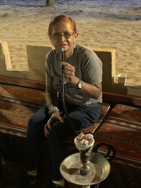 A woman seated with a hookah on a carpet.