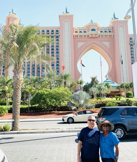 A large hotel with flags and cars in front.