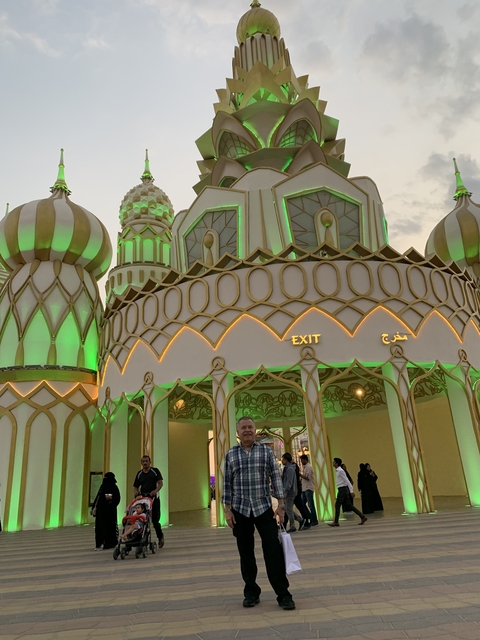 A man standing in front of an ornately designed entrance with lights.