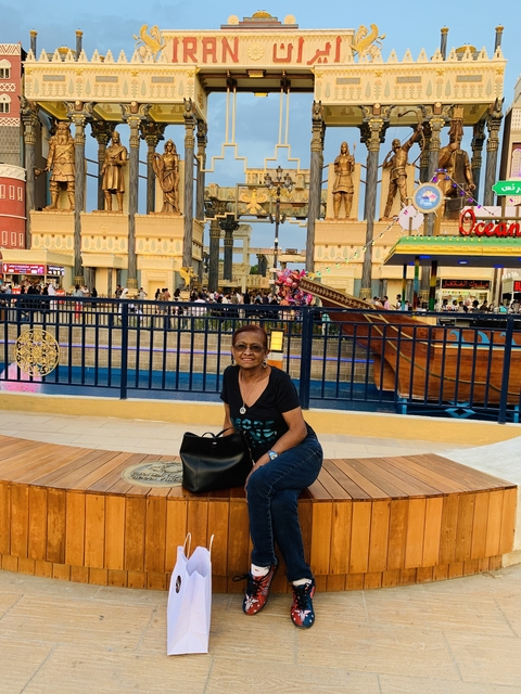 A woman sitting in front of a bustling amusement park area.