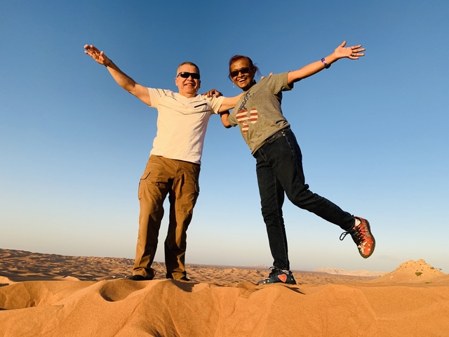 A couple posing on sand dunes with a clear sky.