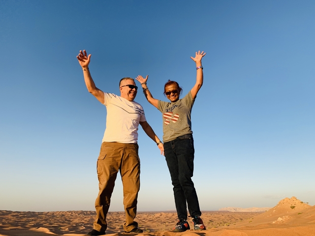 A couple jumping in the desert with clear skies.