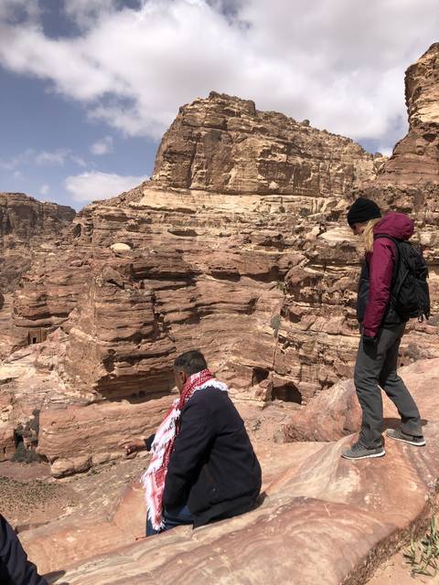 People sitting on rocks near a cliff.