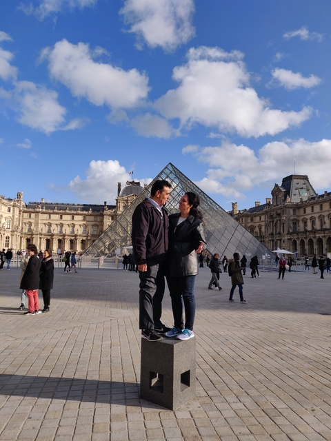 Couple posing in front of the iconic Louvre Pyramid.