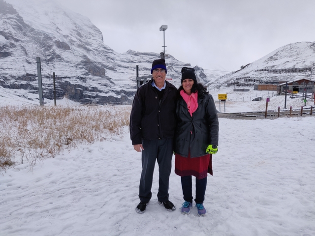 Couple posing in a snowy landscape by a cable car station.