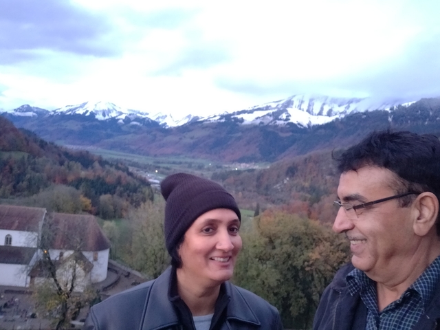 Two people posing with a mountainous landscape in the background.
