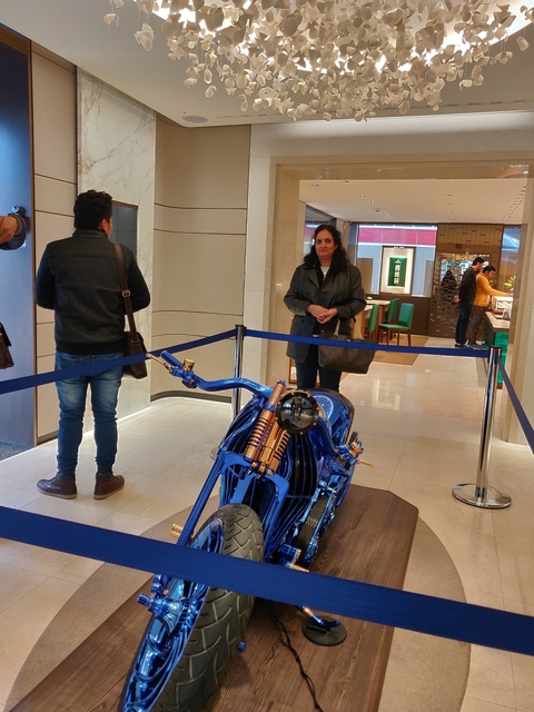 People admiring a blue motorcycle in an indoor setting.