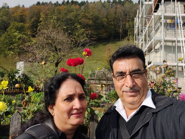 Couple posing in a garden with blooming flowers.