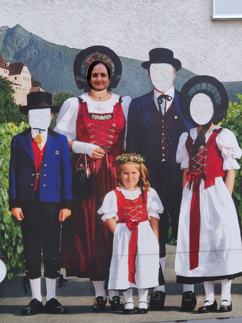 Cutout board with traditional costumes, missing faces.